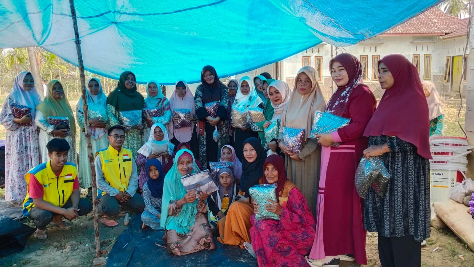 Relawan dalam kegiatan Bansos Sahabat Yatim menyerahkan mukena di Aceh Tamiang.