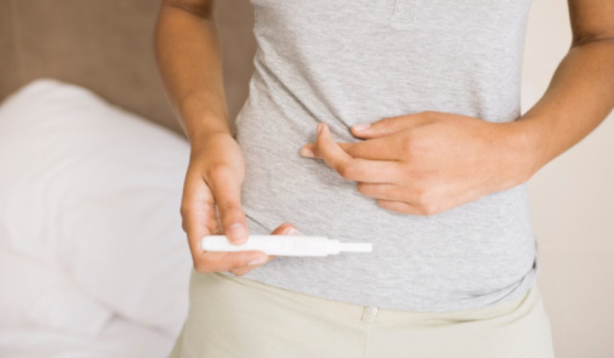 Woman crossing fingers with pregnancy test